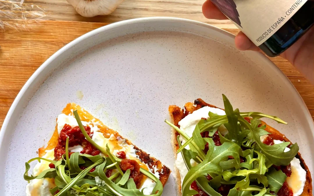 Tostada con aceite de ajo, ricota, tomate confitado y rúcula